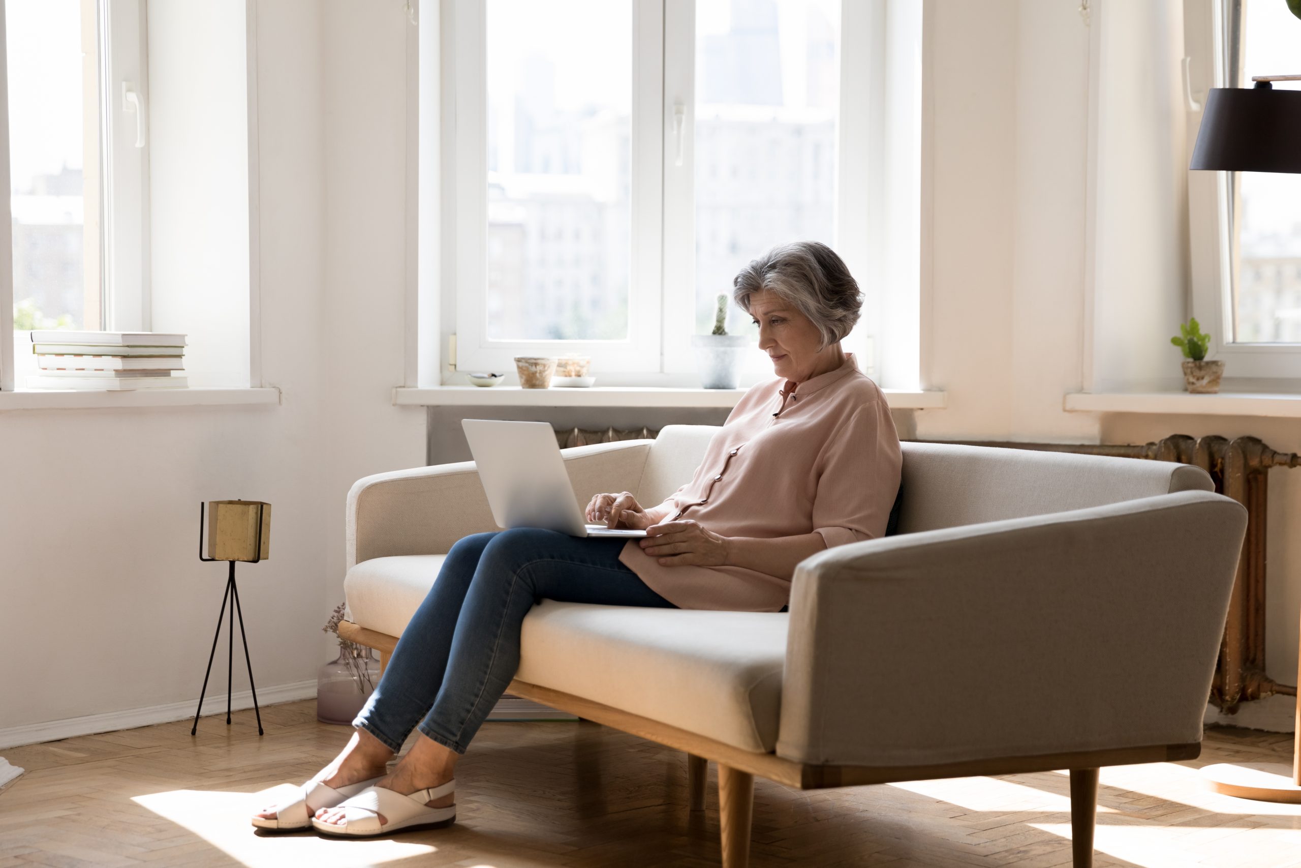 Middle,Aged,Grey,Haired,Freelance,Woman,Using,Laptop,At,Home,